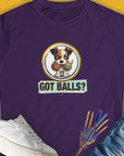A semi-fitted purple tee features a playful puppy with tennis balls and the phrase Got Balls? Volume 5. Funny dog shirt for the playful at heart. Designed by Dog Gang.
