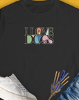 The shirt features a cute dog design with Love Dogs printed in bold letters. Designed by Dog Gang.