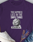 Purple tee features True happiness lies in the simple things, my dog knows that, showing a simple tennis ball. Perfect for any dog lover. Designed by Dog Gang.