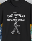 The black T-shirt features a funny quote: My Dog Is Easily Distracted By - Volume 5: People With Four Legs, with a cartoon of someone walking with walking sticks. Designed by Dog Gang.