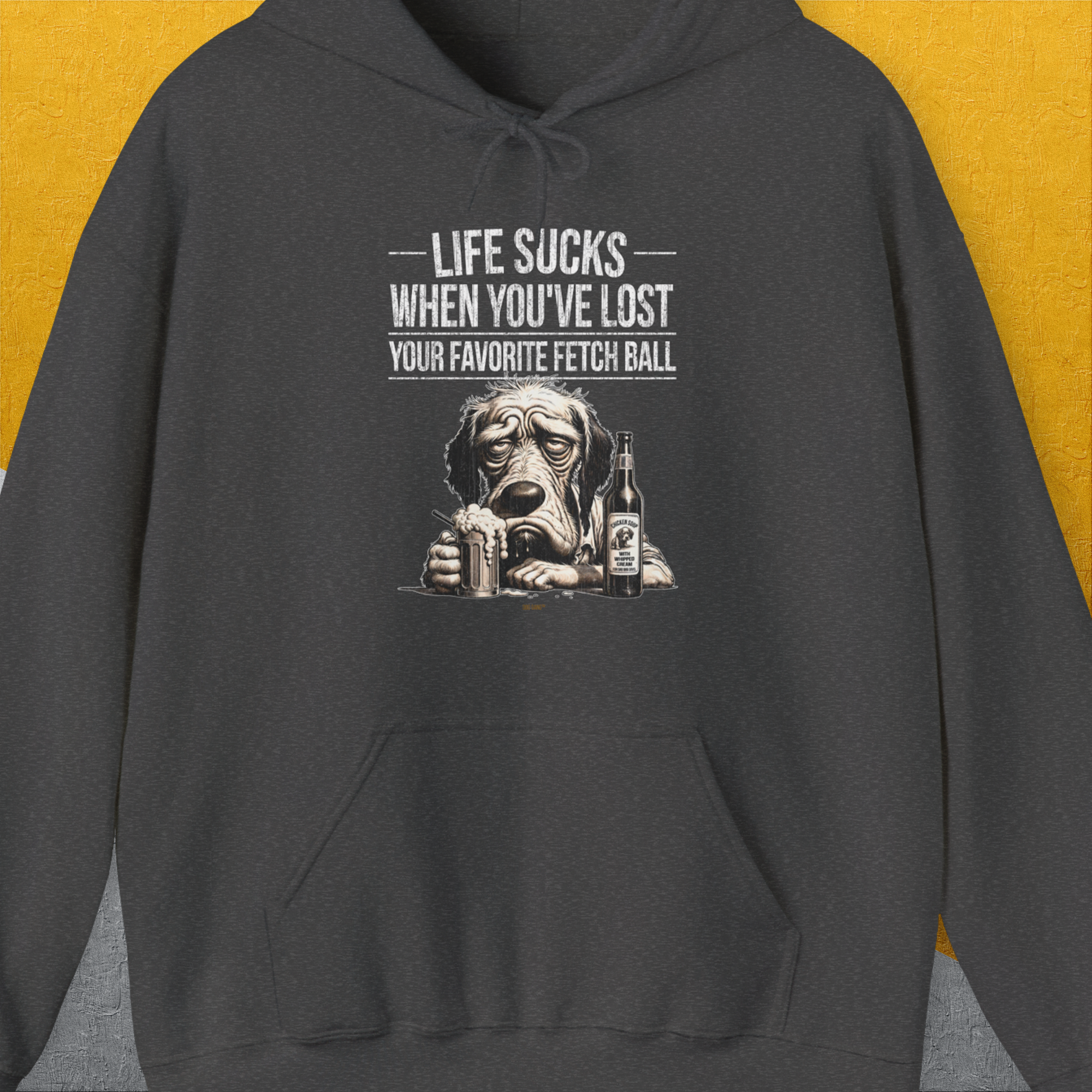 The unisex hoodie features a funny drawn sad dogs face with the quote, Life Sucks When Youve Lost Your Favorite Fetch Ball. Next to the dog is a full glass and a bottle with a label that says: "Chicken Soup with whipped cream, for sad dog days". Perfect for any dog person. Designed by Dog Gang.