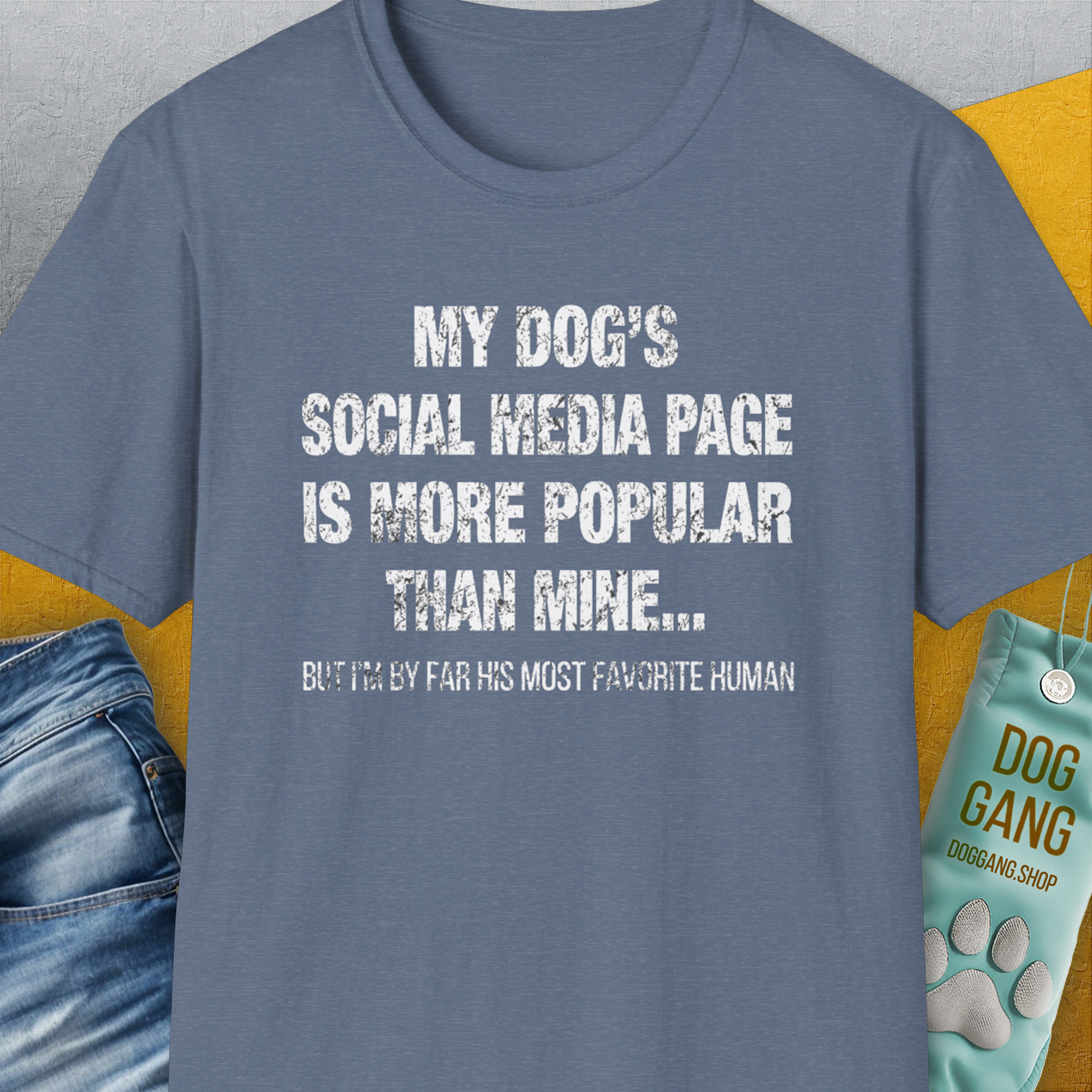 This funny dog shirt in heather indigo features the quote: My dogs social media page is more popular than mine... But Im by far his most favorite human. Designed by Dog Gang.