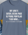 This funny dog shirt in heather indigo features the quote: My dogs social media page is more popular than mine... But Im by far his most favorite human. Designed by Dog Gang.