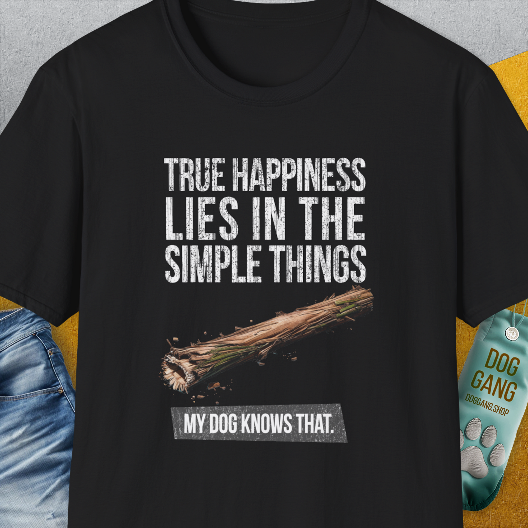 The True Happiness Series One, Volume 2 Unisex T-Shirt is black with a comfy cotton-polyester mix. It has the saying: True happiness lies in the simple things. My dog knows that. plus a simple wooden stick image. Designed by Dog Gang.