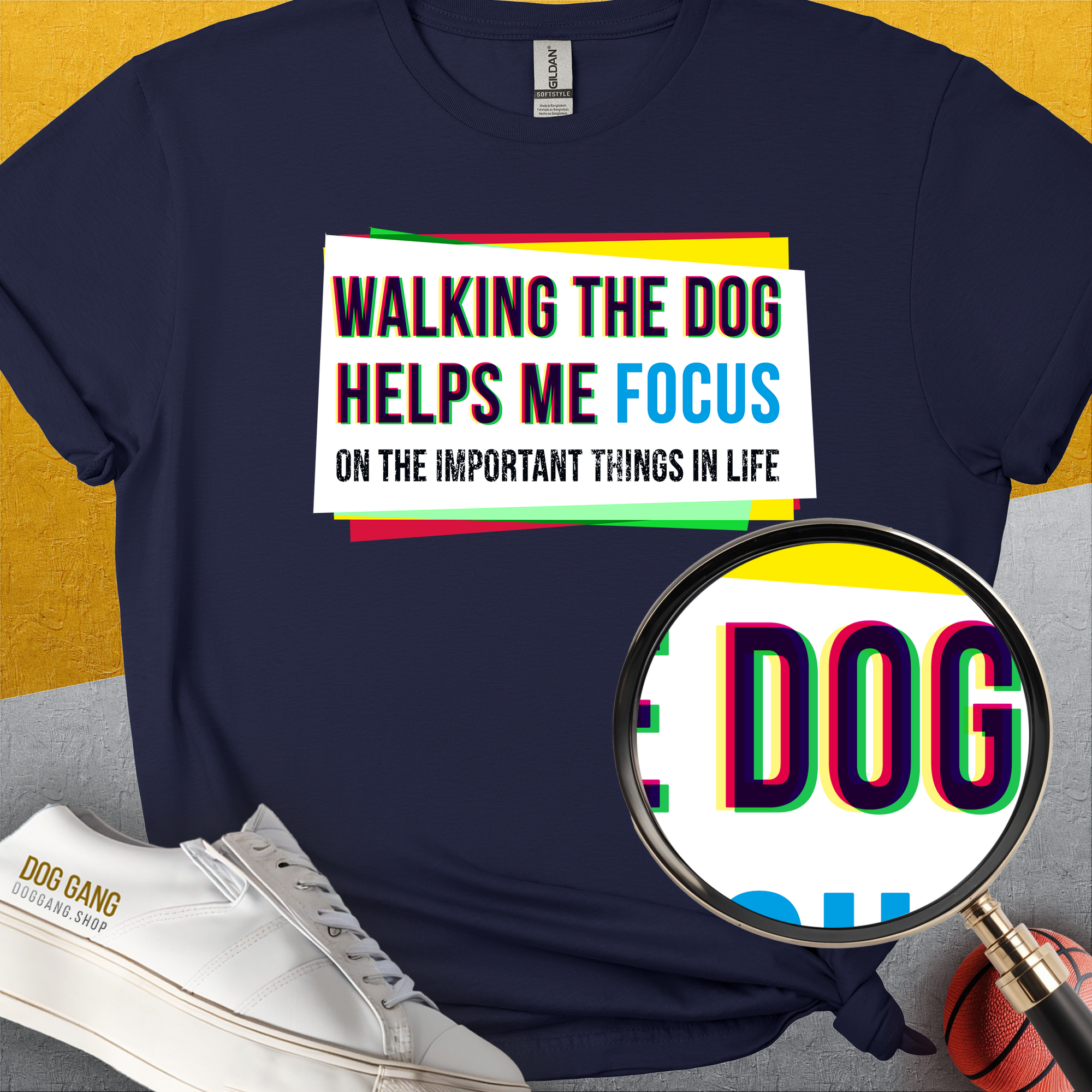 Navy blue shirt featuring a funny dog design with a quote: Walking the dog helps me focus on the important things in life, alongside shoes and a ball. Designed by Dog Gang.