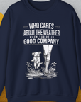 USA navy sweatshirt with a playful dog splashing in boots, featuring the saying Who Cares About The Weather When Youre In Good Company, Volume 2. Perfect for any dog lover. Designed by Dog Gang.