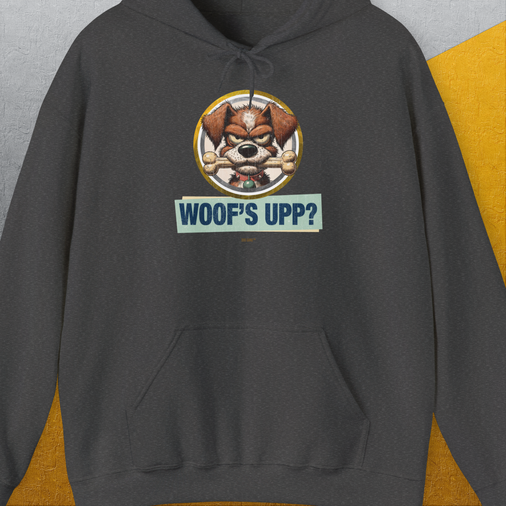 The Woofs Upp? Volume 2 hoodie highlights a funny dog design with a playful pup holding a bone and the text WOOFS UPP?. Perfect for any dog lover. Designed by Dog Gang.