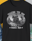 The Walking The Dog, Western Style, Volume 3 unisex T-shirt in black is crafted from soft-style cotton with a funny dog design of a cowboy and his dog. Designed by Dog Gang.