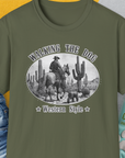 Military green shirt with a cowboy and hat graphic, called Walking The Dog, Western Style, Volume 1. Designed by Dog Gang. Perfect for the dog lover who enjoys a comical twist!.