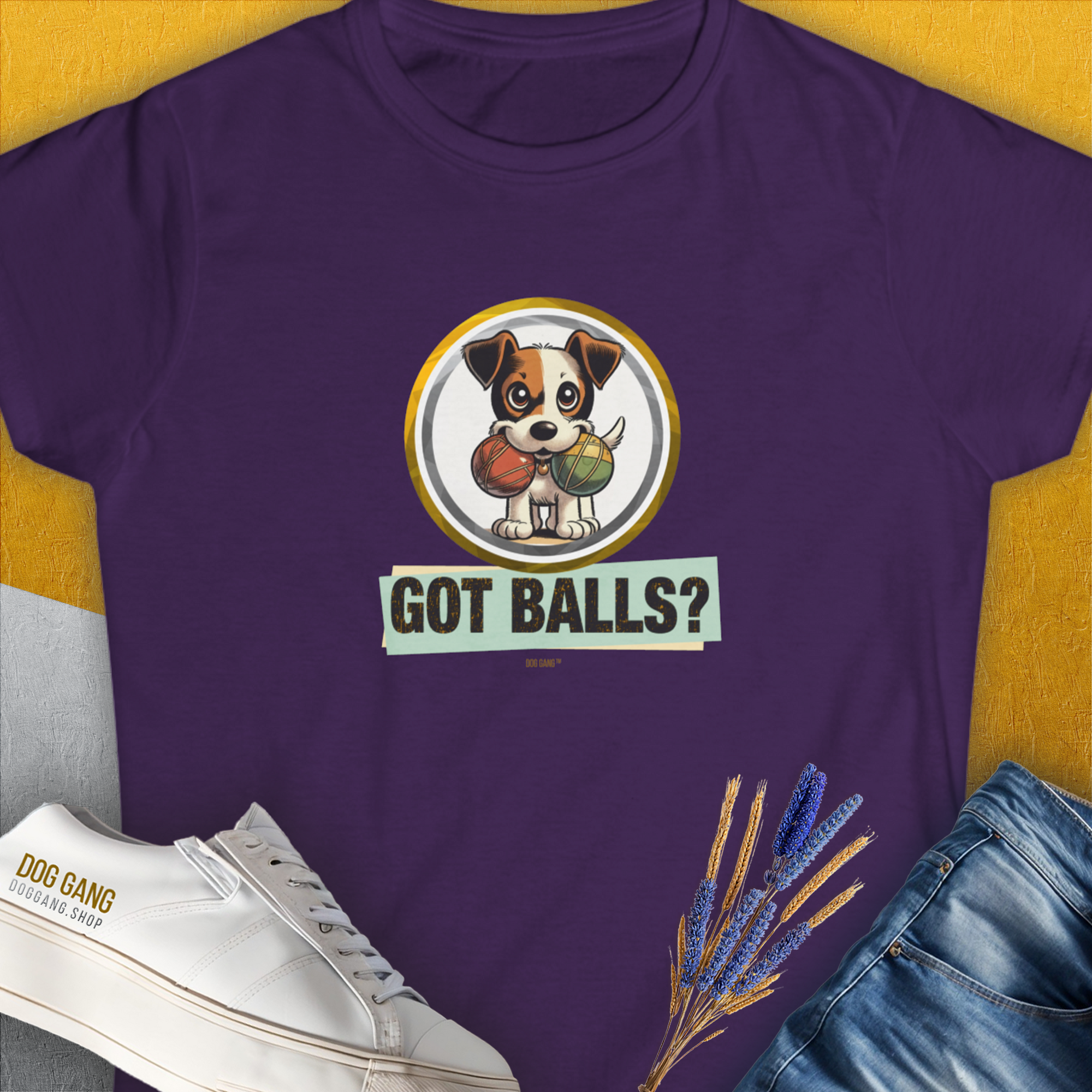 A semi-fitted purple tee features a playful puppy with tennis balls and the phrase Got Balls? Volume 5. Funny dog shirt for the playful at heart. Designed by Dog Gang.