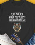 The black T-shirt showcases a German Shepherd and the humorous quote Life Sucks When Youve Lost Your Favorite Fetch Ball, Volume 4. A funny dog shirt perfect for any dog lover. Designed by Dog Gang.