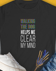 The Walking The Dog Series One, Volume 3 womens tee in black showcases WALKING THE DOG HELPS ME CLEAR MY MIND with white shoes. Perfect for the dog lover seeking a cute dog design. Designed by Dog Gang.