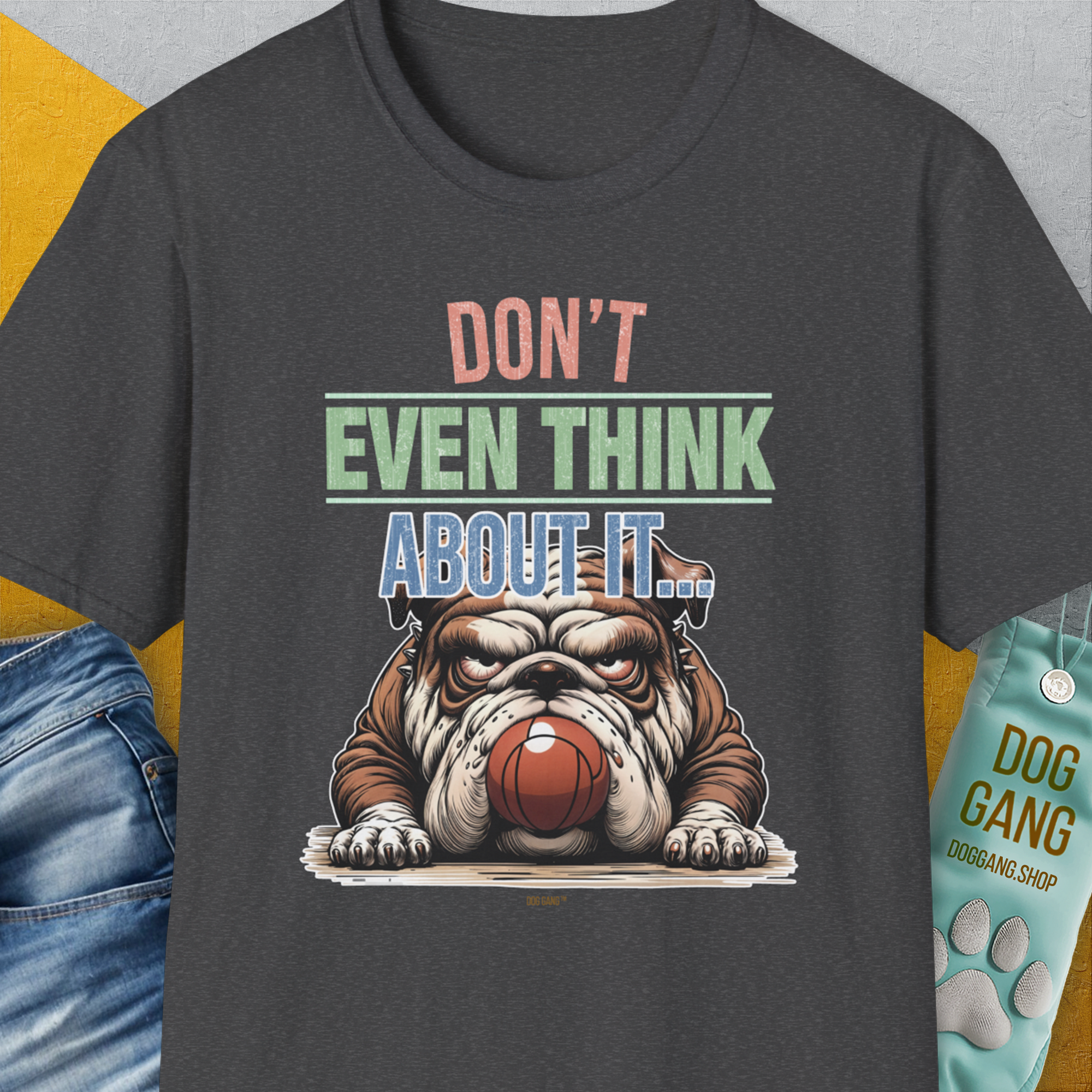 This dark heather unisex t-shirt features a funny bulldog guarding a fetch ball graphic with the saying Dont Even Think About It... and a small DOG GANG tag. Designed by Dog Gang.