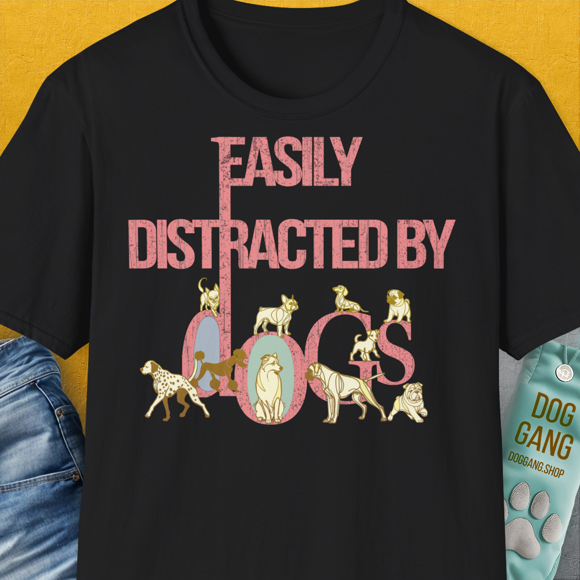 The black unisex t-shirt from the Easily Distracted By Dogs Series, Volume 2 highlights a dog-themed design with pink text and playful dog illustrations creatively forming the word dogs. The illustrations include breeds like Dalmatian, Golden Retriever, Pug, Poodle, Dachshund, Bulldog, Chihuahua, Husky and more. Designed by Dog Gang.