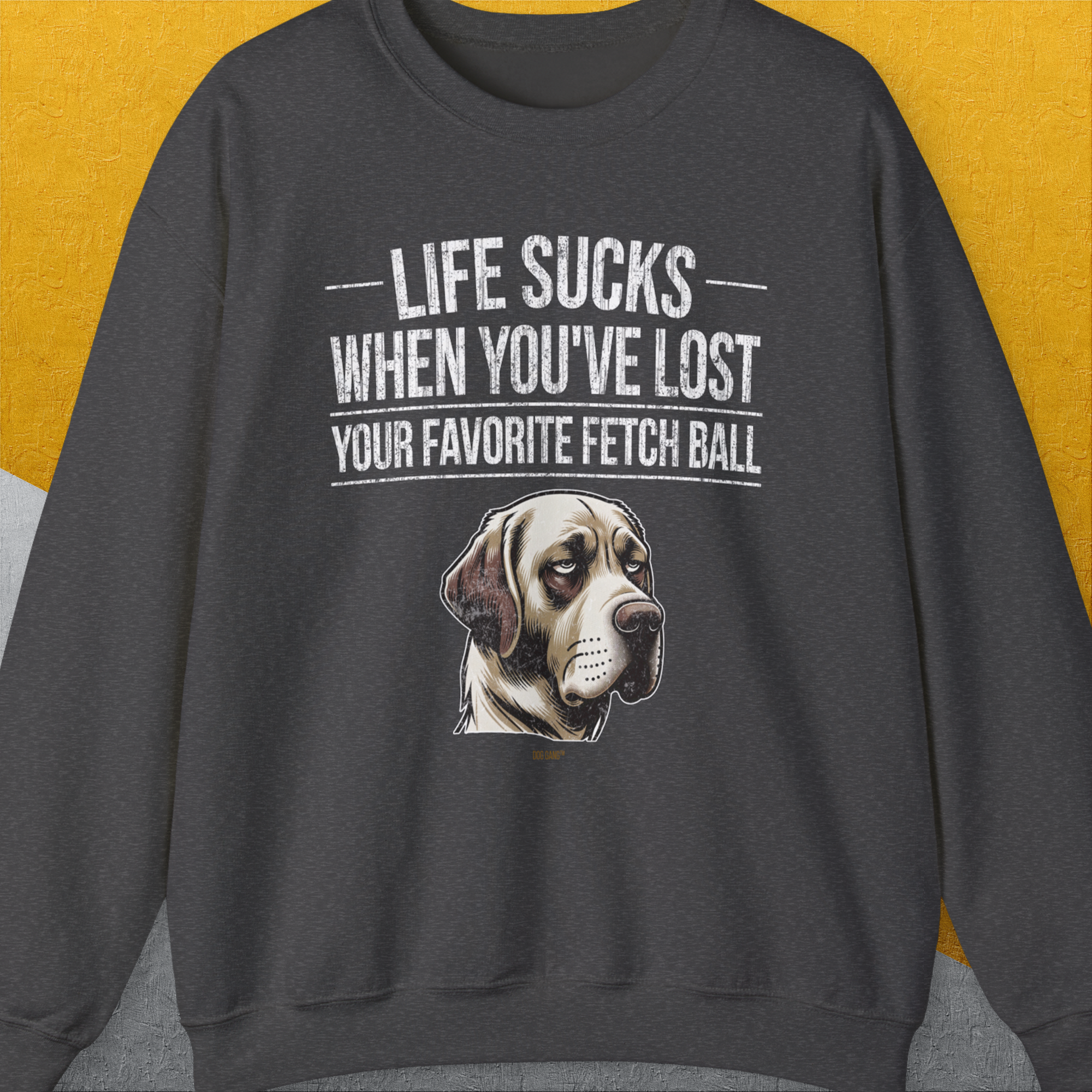 Unisex sweatshirt titled Life Sucks When Youve Lost Your Favorite Fetch Ball, Volume 1 in Dark Heather, featuring a sad dog illustration. A perfect funny shirt for any dog lover. Designed by Dog Gang.