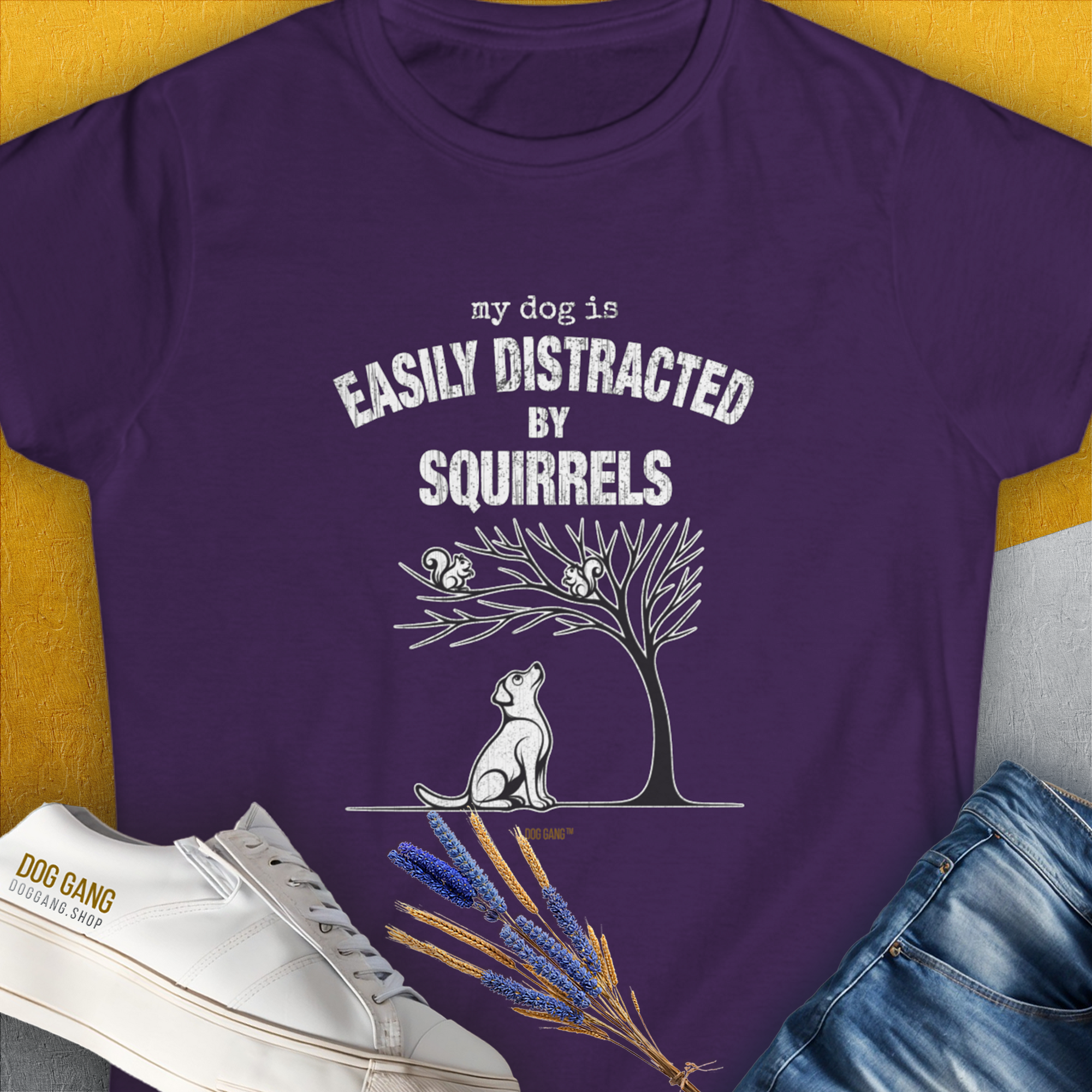 The My Dog Is Easily Distracted By - Volume 1: Squirrels womens T-shirt in purple showcases a funny dog design with a playful pup watching squirrels and the quote my dog is easily distracted by squirrels. Designed by Dog Gang.