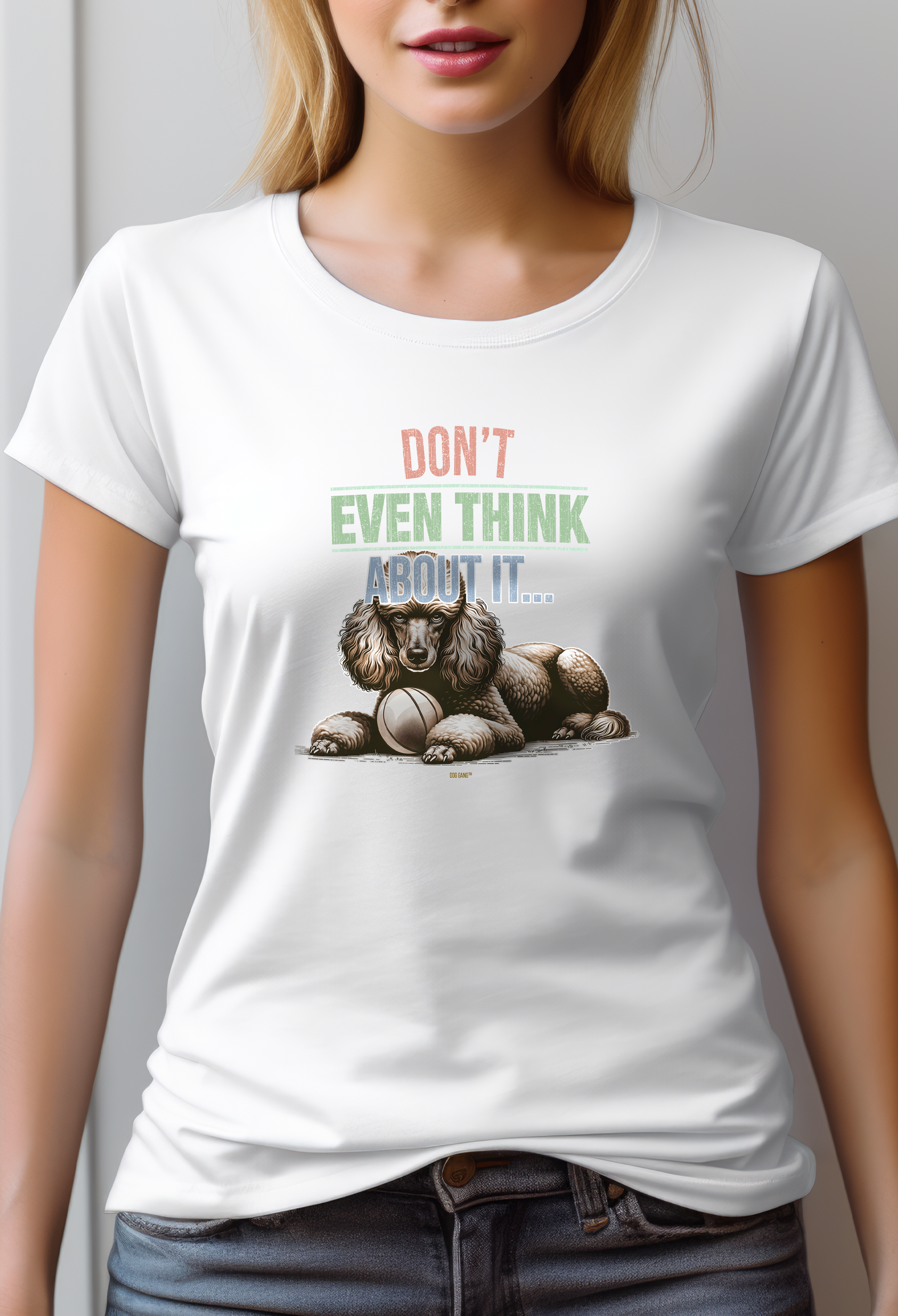 A woman wears a women's white t-shirt designed by DOG GANG with a graphic of a serious looking poodle lying down with a ball next to it. The text above the dog reads: DON'T EVEN THINK ABOUT IT...