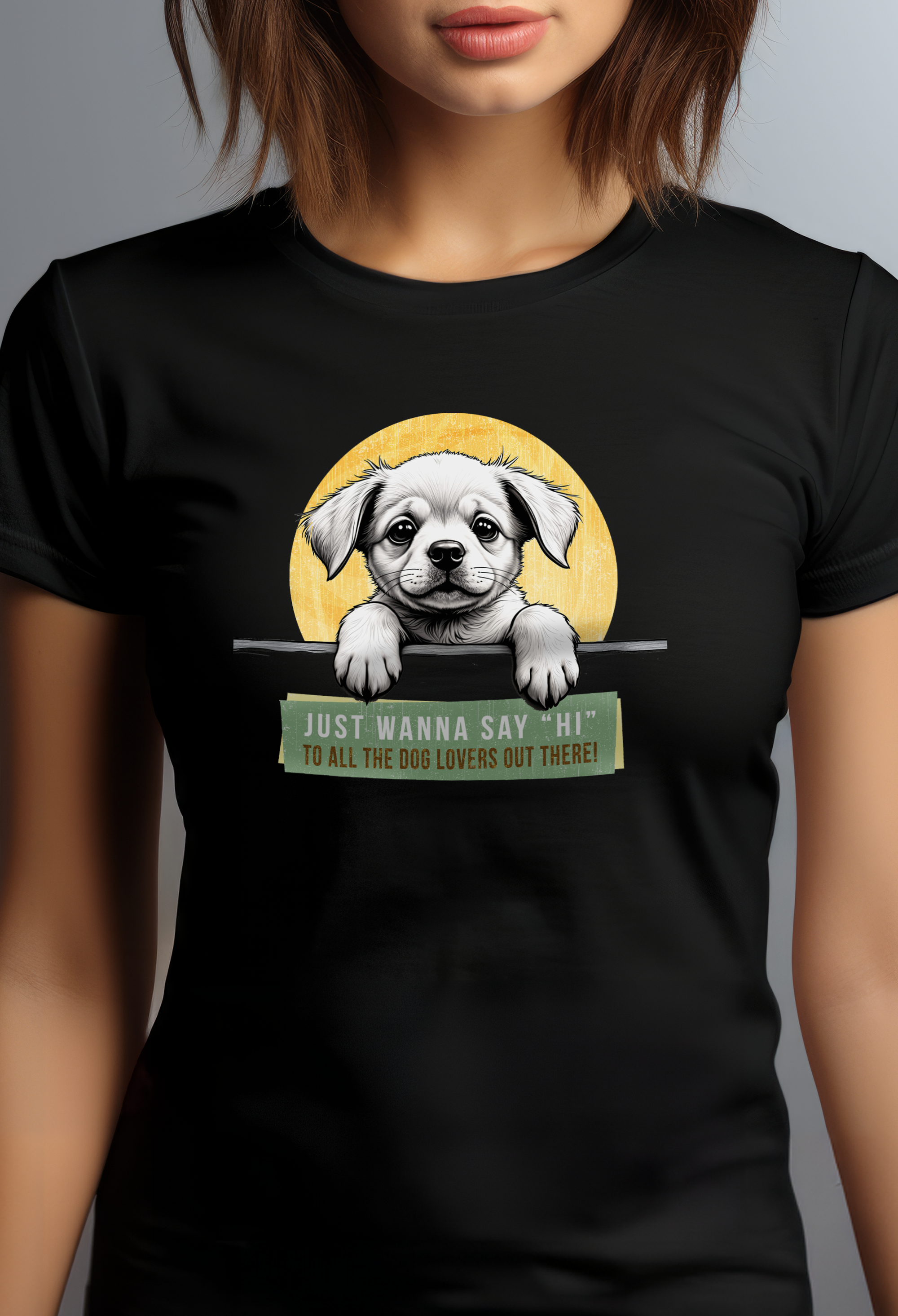 A person is wearing a black t-shirt featuring an illustration of a puppy with its paws over a ledge. The background is a yellow circle, and text below the puppy reads, Just wanna say Hi to all the dog lovers out there!.