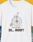 The So... Woof? Volume 3 Unisex T-Shirt in white displays a cartoon dog on a penny-farthing and says, Dogs do dog things. So... Woof? Perfect for any dog lover. Designed by Dog Gang.
