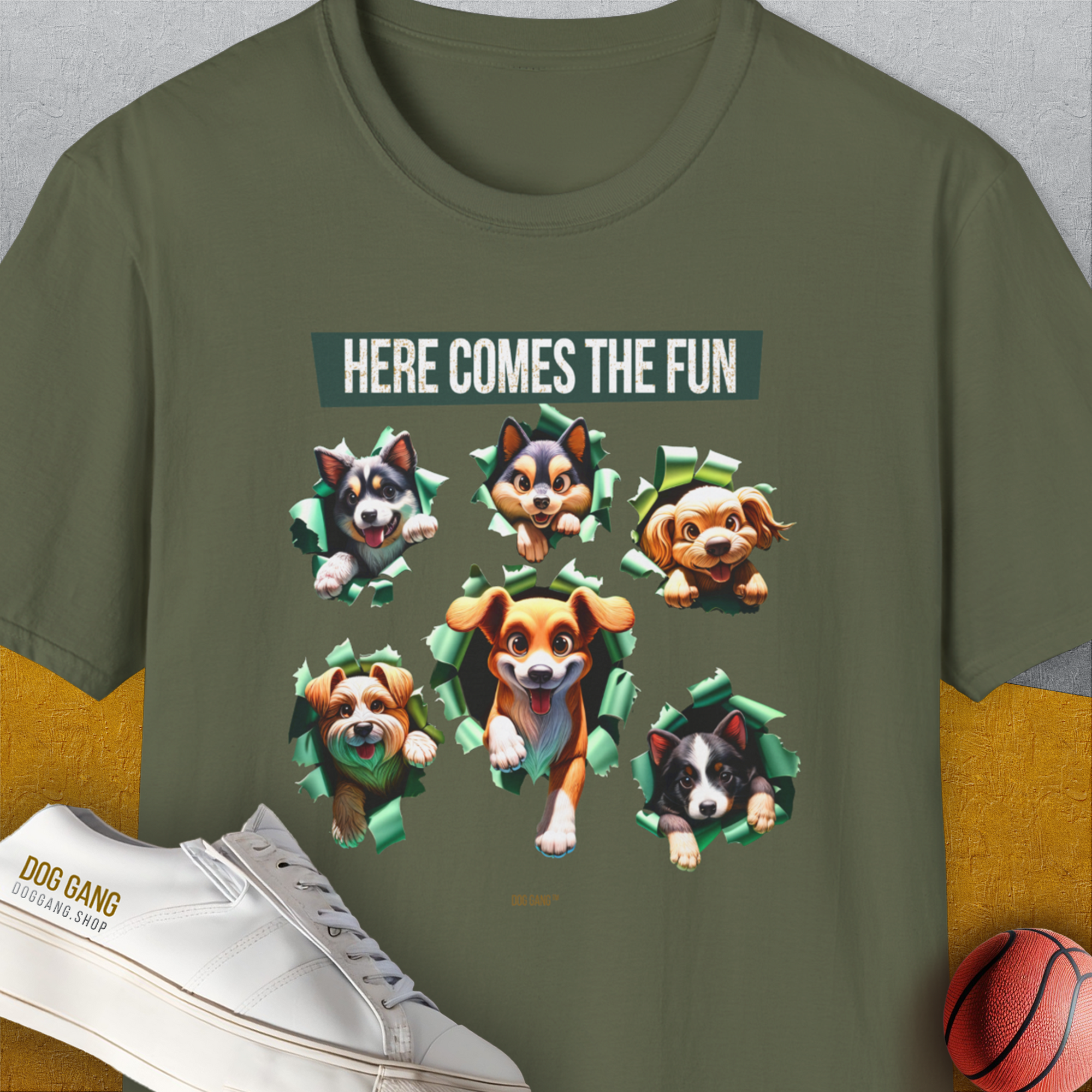 Military green tee with cartoon dogs and the text Here Comes The Fun. A funny dog shirt for playful spirits. Designed by Dog Gang.